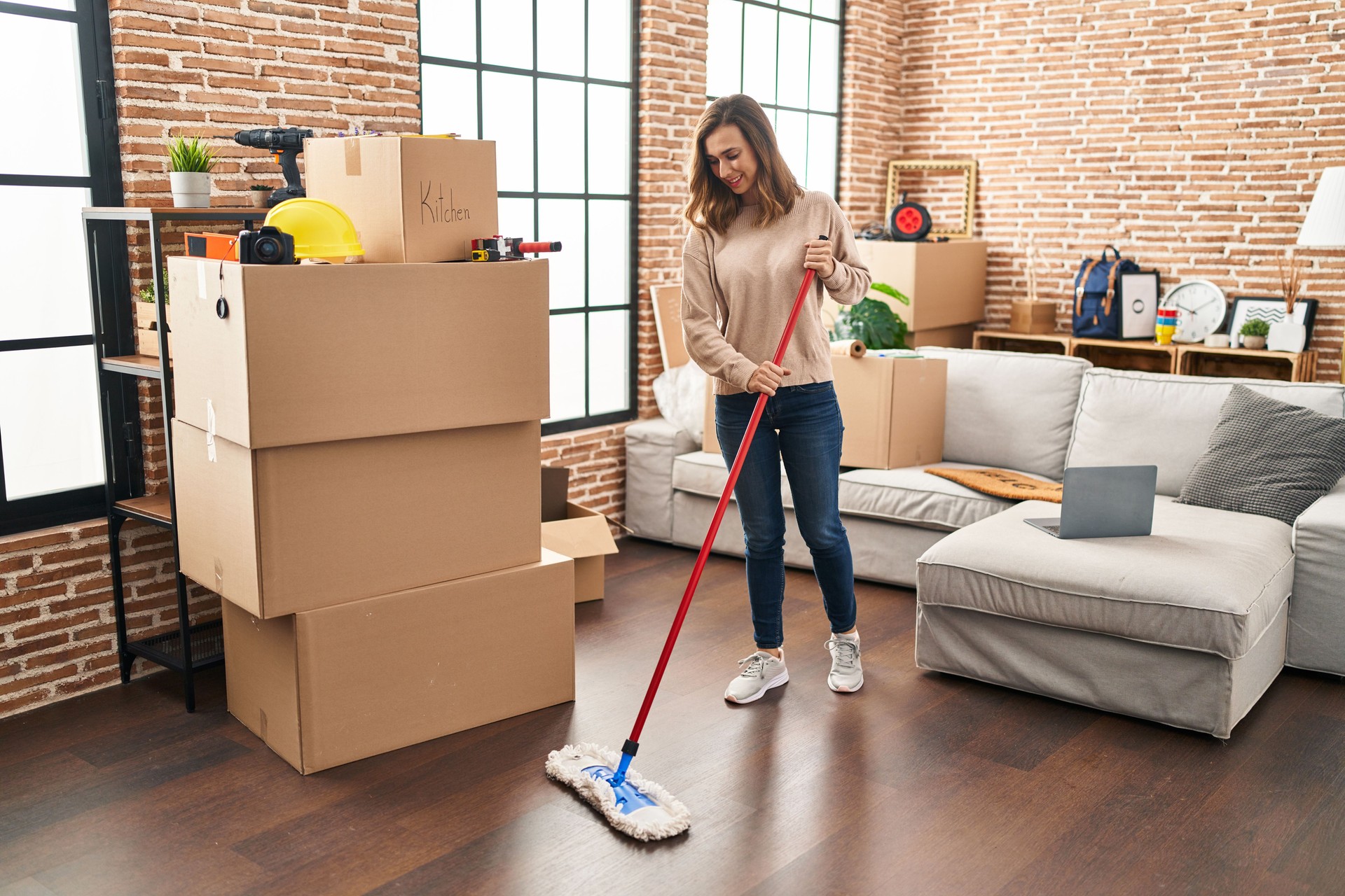 Young woman smiling confident cleaning floor at new home